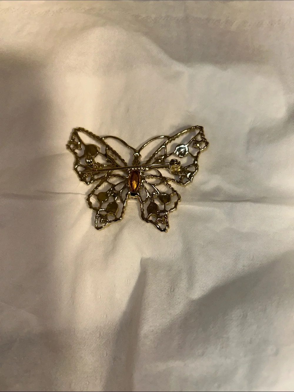 Dodds filigree butterfly brooch featuring a large amethyst-colored center stone